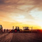 Agricultural mechanization preparing land for seeding on a sunset.
