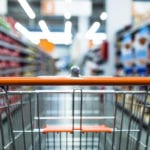 Abstract blurred photo of store with trolley in department store background. Supermarket aisle with empty red shopping cart