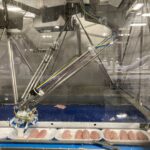 Dans l'usine d'Olymel à Saint-Damase, un robot sélectionne et place de poitrine de poulet dans des barquettes.