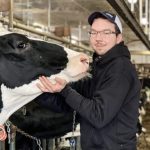 Francis Lessard pose avec une vache dans son étable.